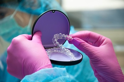 Dental professional holding custom clear aligners used for Invisalign orthodontic treatment